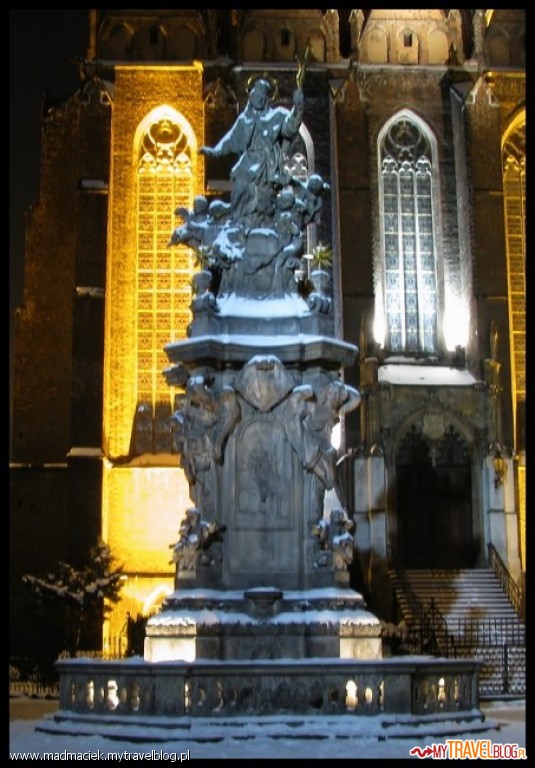 Rzeźba św. Jana Nepomucena. W tle dwukondygnacyjny kościół św. Krzyża i św. Bartłomieja